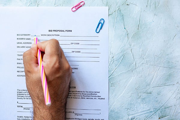 Close up of a hand holding a pen and filling out an application.