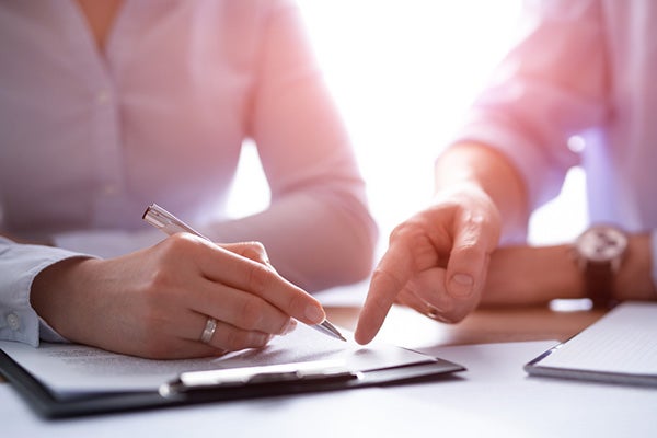 Two people looking over papers on a clipboard.
