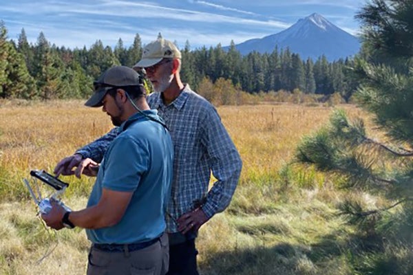 Two men in the field with the mountain in the background