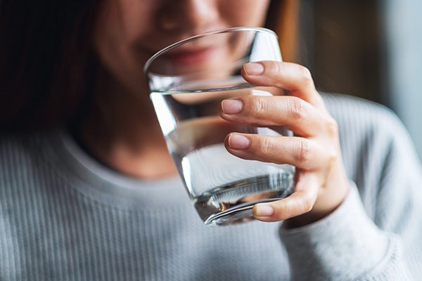 woman holding a crisp glass of water up to her mouth.